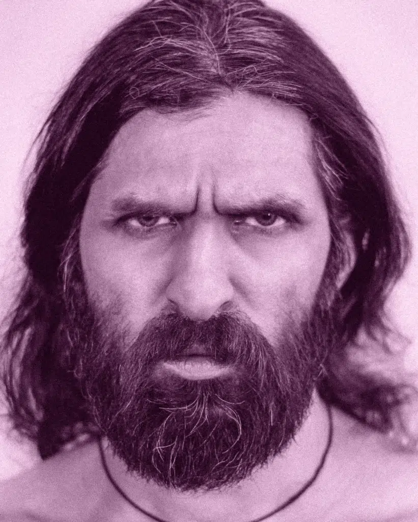 A man with long hair and beard wearing a necklace.