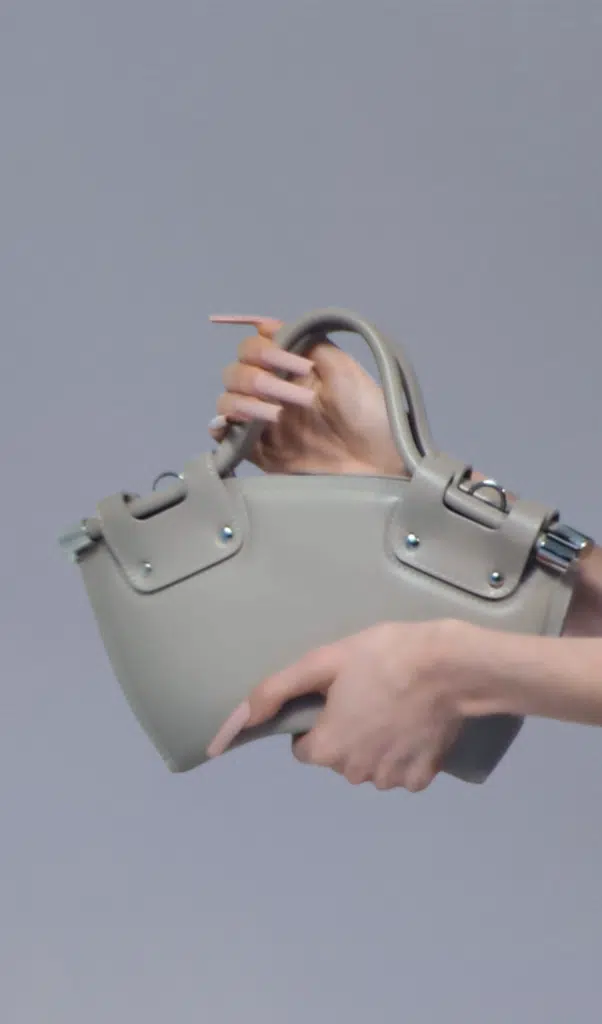 A person holding onto a gray purse