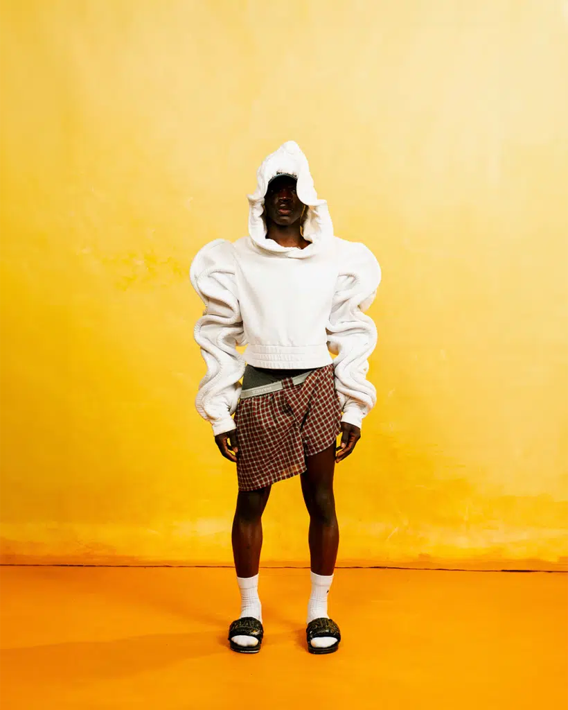 A person standing in front of a yellow wall.