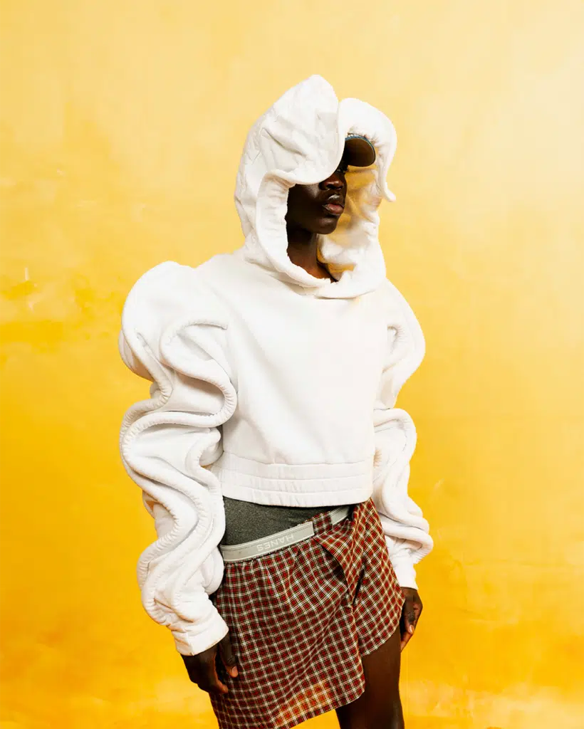 A person wearing a white hoodie and plaid pants.