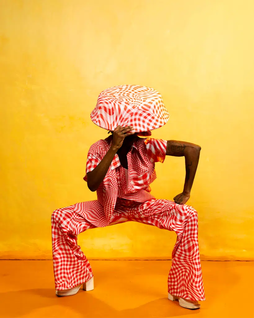 A person in red and white clothing sitting on a chair.